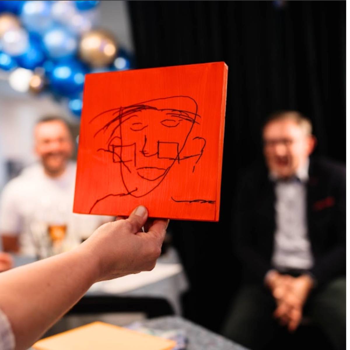 Gast zeigt sein Blind Portrait auf roter Leinwand beim Firmenfest